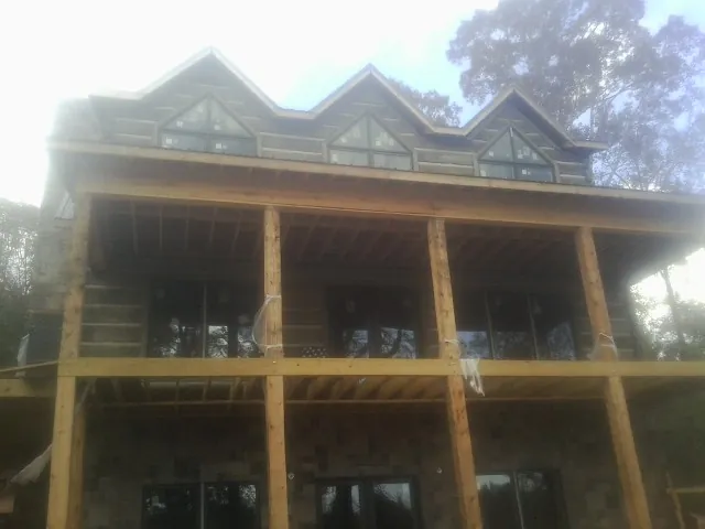Dormers and porch framing on a large log home under construction — Roof Coating work by our crew in Winthrop Harbor