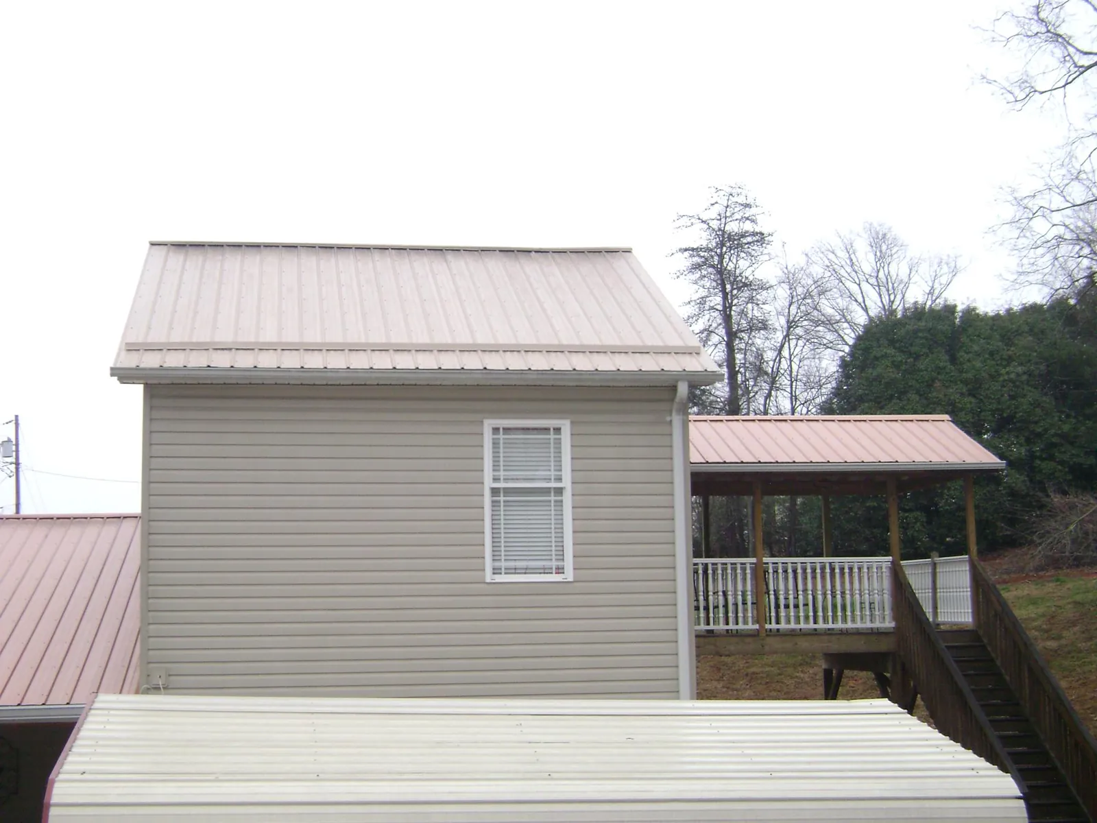 Tan metal roofs on a two story addition and attached porch, from a Roof Replacement job in Winthrop Harbor