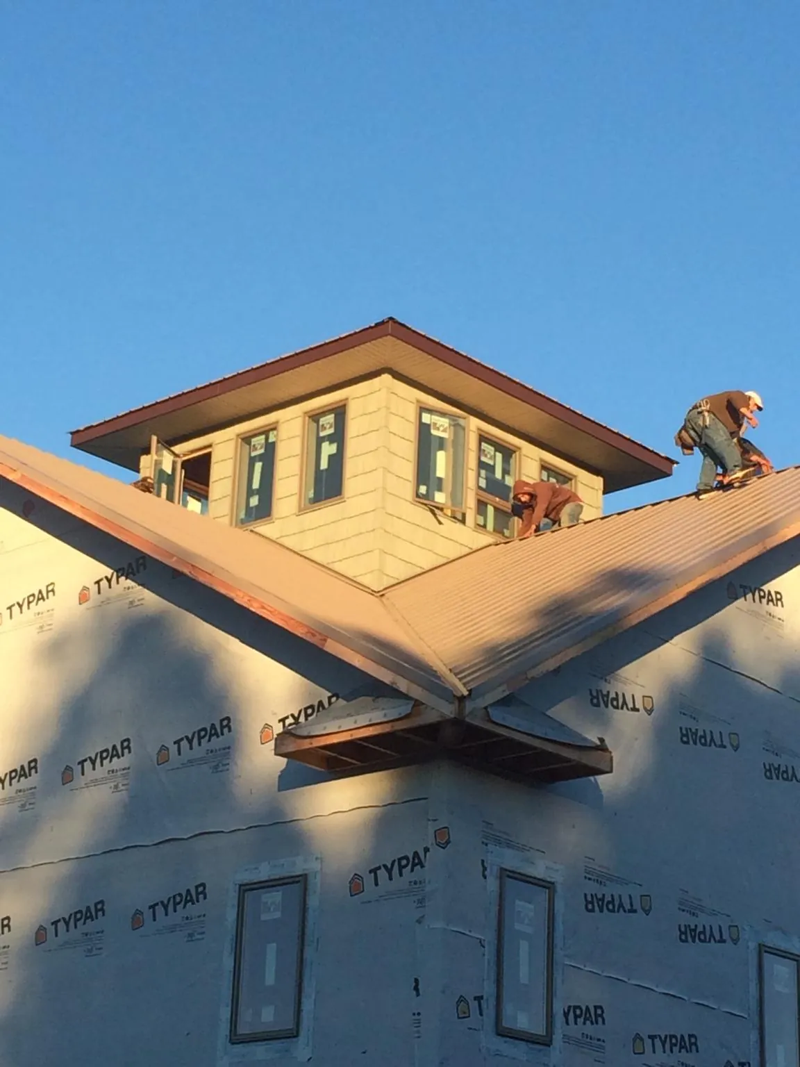 Roofers working around a rooftop cupola on a new metal roof at sunset — Roof Waterproofing in Winthrop Harbor by Roofing Brothers